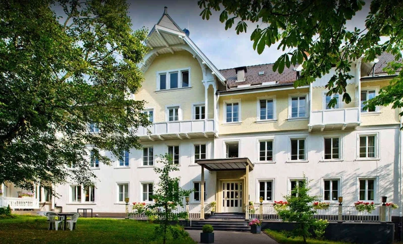 Au&szlig;enansicht der Privatklinik Friedenweiler der Oberberg Kliniken im Gr&uuml;nen mit blauem Himmel
