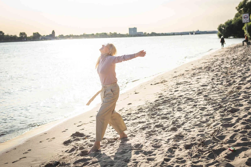 Weit aufnahme von einer Frau am strand mit offenen armen