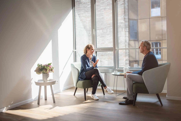 Frau und Mann sitzen vor einem Fenster und unterhalten sich
