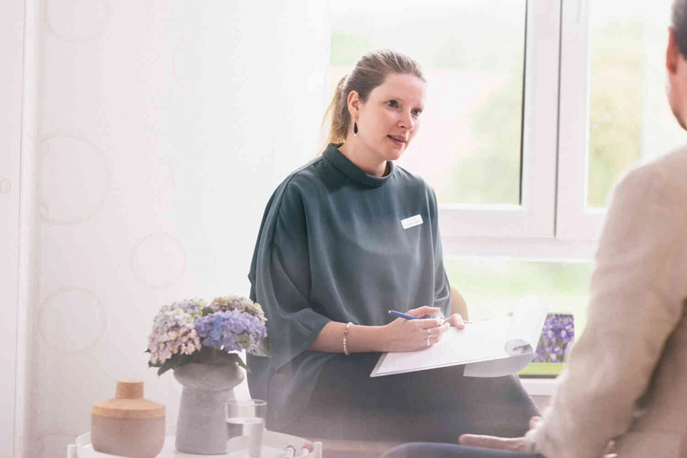 Therapeutin macht sich im Gespr&auml;ch Notizen auf einem Klemmbrett